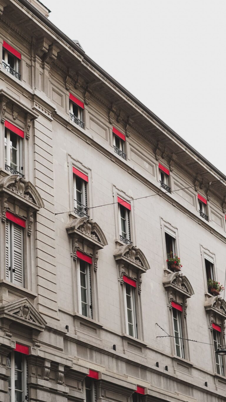 Close-up of a classic architectural facade with red accents in Milan's urban landscape.