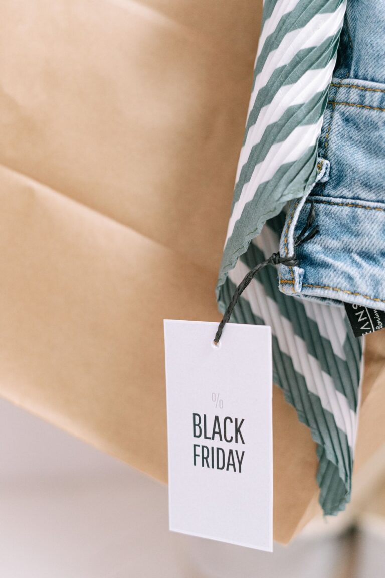 Close-up of Black Friday discount tag tied to denim and striped clothing.