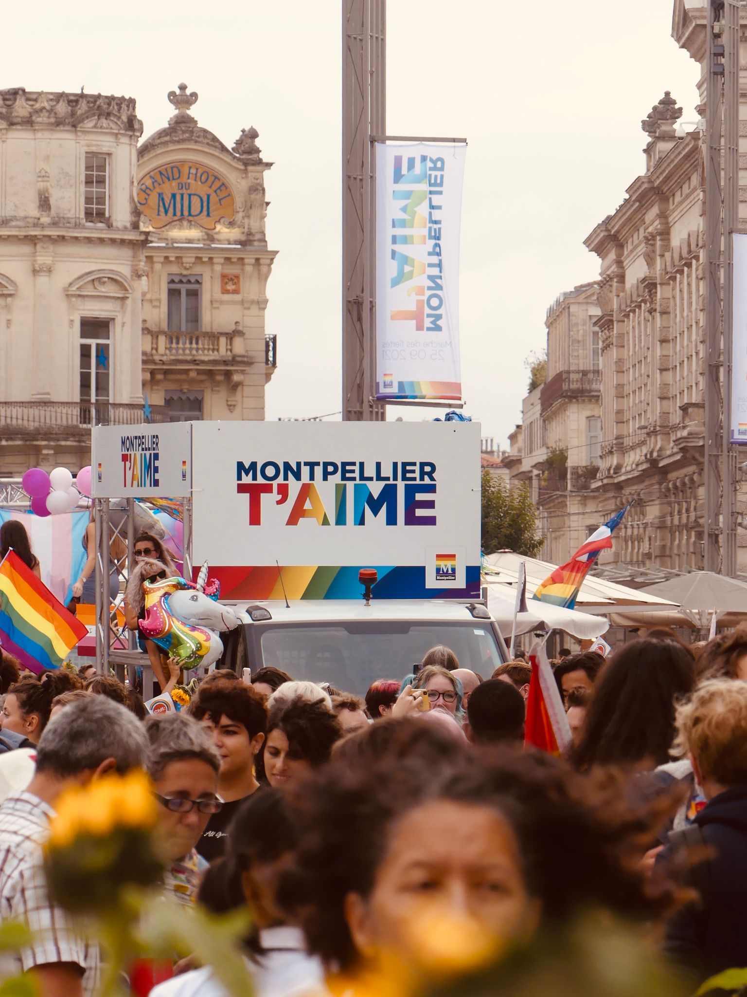 Colorful LGBT pride event in Montpellier, France with a lively crowd and rainbow flags.