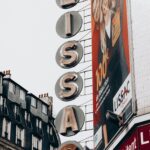 Low angle of advertisement with photo against title on optics building under light sky in city